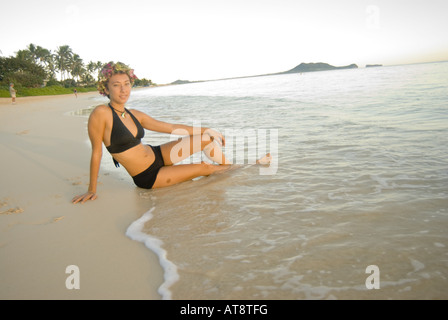 Schöne junge Frau trägt einen schwarzen Badeanzug lounges am Ufer am weltberühmten Strand Lanikai auf der windzugewandten Seite von Oahu. Stockfoto