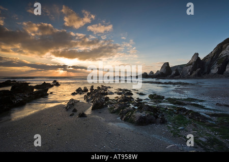 Dramatische Beleuchtung und Sunburst über die zerklüftete Küste am Westcombe Strand, Devon, England Stockfoto