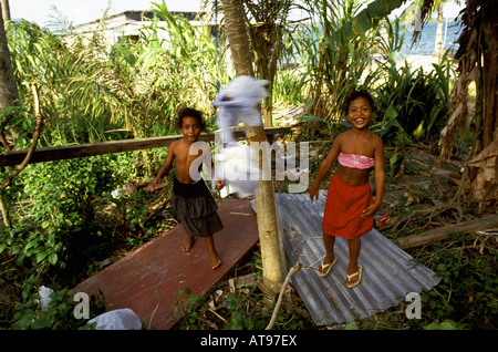 Zwei lächelnde Mädchen spielen mit home made Tether Ball in ihrem Vorgarten, Yap, Mikronesien. Stockfoto