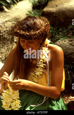 Junge Mädchen tragen ein Haku Lei macht Plumeria Leis an den Waimea Falls auf der Insel Oahu, Hawaii. Stockfoto