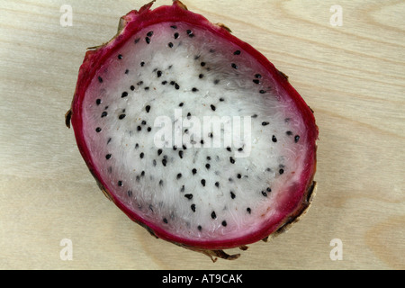 Eine halbe weiße konkretisiert Drachenfrucht. Kleinen schwarzen Samen in weißen Fleisch auf hellem Holz Hintergrund. Stockfoto