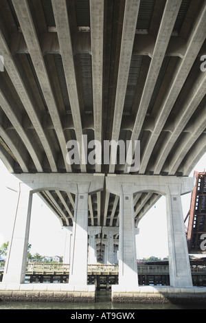 Unterseite der Straßenbrücke.  Parallele Betonbalken mit großen Betonpfeilern über schmalen Meeresarm. Stockfoto