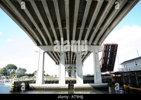 Unterseite der Straßenbrücke.  Parallele Betonbalken mit großen Betonpfeilern über schmalen Meeresarm Stockfoto