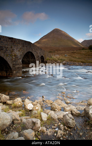 alte gewölbte Brücke und Fluss bei Sligachan auf der Isle Of Skye in Schottland mit Glamaig oder Sgurr Mhairi Berg im Hintergrund Stockfoto