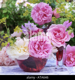 Blumenstilleben mit Rosen, Pfingstrosen und Zuckererbsen und Cranberry Glas in einen englischen Garten Stockfoto