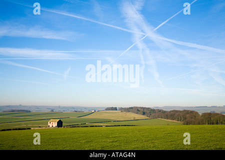 Umweltschädliche Flugzeugen Routen in den Himmel über den Peak District zeigt ein einsames Land Bauernhaus in der Landschaft Stockfoto