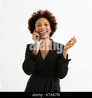 Frau am Handy lächelnd vor weißem Hintergrund Stockfoto
