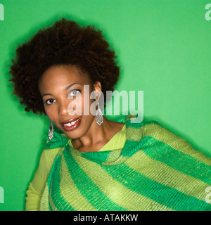 Porträt der Frau mit Afro tragen grün gestreiften Schal auf grünem Hintergrund lächelt Stockfoto