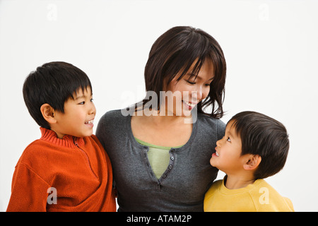 Asiatische Mutter und zwei Söhne, die lächelnd auf einander Stockfoto