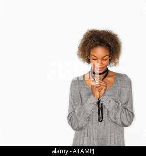 Frau mit den Händen umklammert zusammen im Gebet und Augen geschlossen Stockfoto