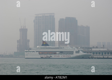 Ein Kreuzfahrtschiff in Hong Kong Hafen Backdropped von Wolkenkratzern an einem Tag mit übermäßigen Luftverschmutzung Stockfoto