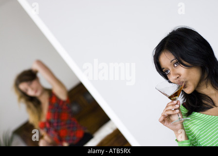 zwei junge Frauen trinken Sherry, eine Darkhaired Frau im Vordergrund, eine blonde Frau hinter Stockfoto