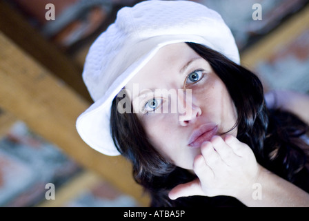 niedliche dunkelhaarige Frau mit Fashinable Kappe, tut einen Luft-Kuss Stockfoto