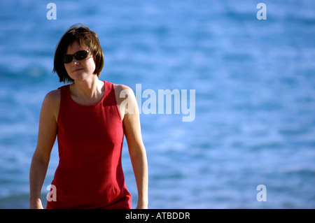 Single-kaukasischen Frau in Sonnenbrille blau Meer rot Kleid cool attraktive Brünette kurze Haare weiblichen horizontale Farbe Farbe Stockfoto