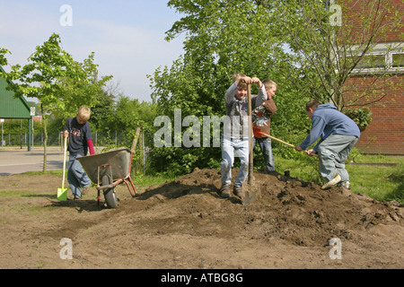 Kinder füllen sich Boden im Garten einer Grundschule, einem Blumenbeet zu bauen Stockfoto
