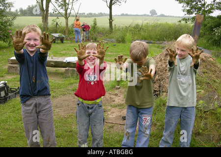 Kinder einer Grundschule hat einen Ofen aus Brickearth zeigen ihre schmutzigen Hände bauen Stockfoto