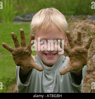 Kind von einer Grundschule hat einen Ofen aus Brickearth zeigt seine schmutzigen Händen bauen Stockfoto