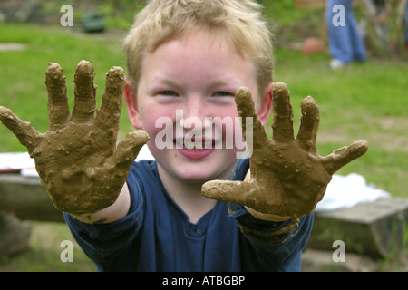 Kind von einer Grundschule hat einen Ofen aus Brickearth zeigt seine schmutzigen Händen bauen Stockfoto