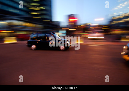 Schwarzes londoner Taxi bei Nacht mit Bewegungsunschärfen, um die Bewegung zu zeigen Stockfoto