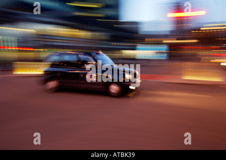 Schwarzes londoner Taxi bei Nacht mit Bewegungsunschärfen, um die Bewegung zu zeigen Stockfoto