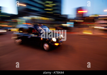 Schwarzes londoner Taxi bei Nacht mit Bewegungsunschärfen, um die Bewegung zu zeigen Stockfoto