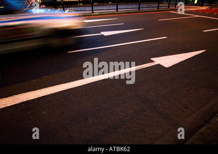 Weiße Straßenpfeile zeigen die Geschwindigkeit des vorbeifahrenden Verkehrs an Stockfoto