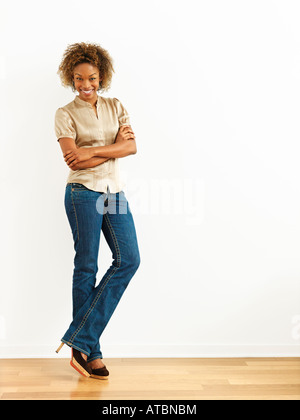 Porträt der Frau, die gegen die weiße Wand lächelnd Stockfoto
