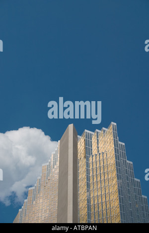 Ein Golden verspiegelte Wolkenkratzer vor einem blauen Himmelshintergrund mit weißen flauschigen Wolke Stockfoto