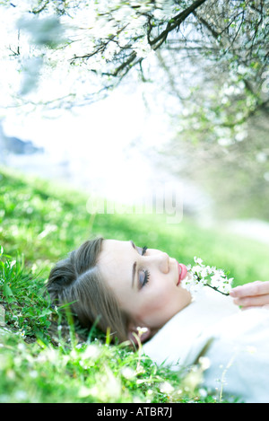 Teenager-Mädchen auf dem Boden liegend riechende Blume, Augen geschlossen Stockfoto