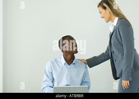 Teenager sitzen, mit Laptop-Computer, Geschäftsfrau, die neben ihm stand lächelte Stockfoto