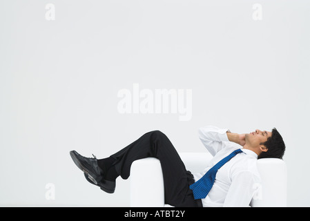 Geschäftsmann liegen seitlich im Sessel, Telefonanruf, in voller Länge Stockfoto