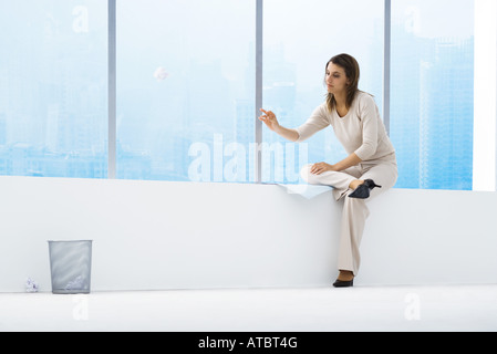 Frau wirft Papier Ball in Richtung Mülleimer Stockfoto