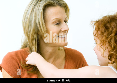 Mädchen berühren ihrer Mutter Haare, lächelnd, Nahaufnahme Stockfoto