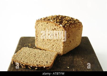 Laib Vollkornbrot und Scheibe auf Schneidebrett Stockfoto