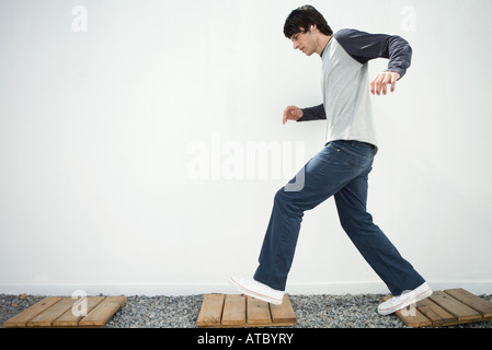 Jungen Mann zu Fuß auf Weg, zuhören, Kopfhörer, Seitenansicht Stockfoto