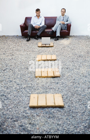 Zwei Geschäftsleute sitzen auf der Couch im Kies, blickte auf Laptop-Computer, Mitteldistanz Stockfoto