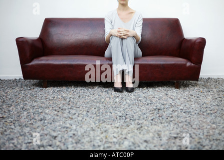 Frau sitzt auf der Couch im Kies, niedrigen Winkel Ansicht, beschnitten Stockfoto