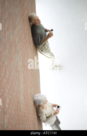 Frau und Mann auseinander stehen, Wand gelehnt, hält Kaffee Tassen, hoher Winkel Ansicht Stockfoto