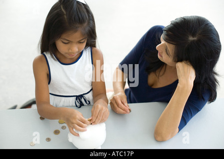 Mutter und Tochter ins Sparschwein zusammen, hoher Winkel Ansicht Münzen Stockfoto