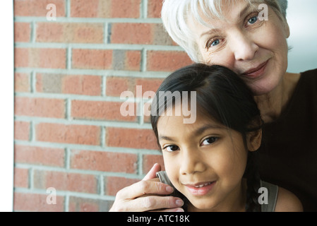 Großmutter, Enkelin, beide lächelnd in die Kamera, umarmen Porträt Stockfoto
