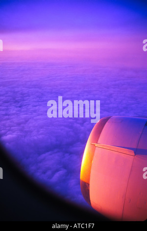 Blick aus dem Flugzeug Fenster Motor Motorhaube und Cloud Bank unten bei Sonnenuntergang Stockfoto