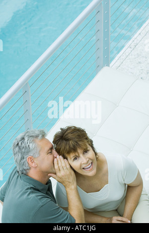 Frau lächelte Kamera als ihr Mann flüstert in ihr Ohr, erhöhte Ansicht Stockfoto