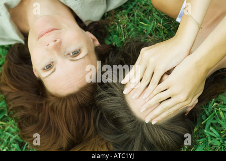 Mutter und Teen Tochter auf dem Boden liegend zusammen, Mädchen für Gesicht mit den Händen, in die Kamera lächelnde Frau Stockfoto