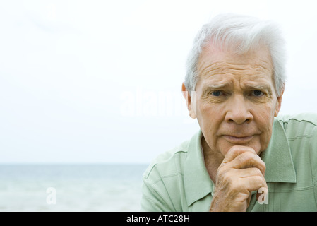 Senior woman gerunzelter Stirn, Hand unter Kinn, Blick in die Kamera Stockfoto