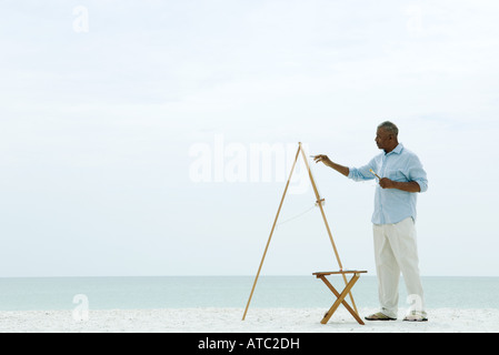 Senior woman Malleinwand am Strand, Seitenansicht Stockfoto