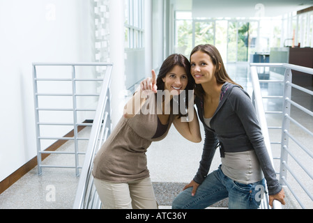 Frau stehend auf Treppen mit Tochter, zeigt, beide auf der Suche und lächelnd Stockfoto