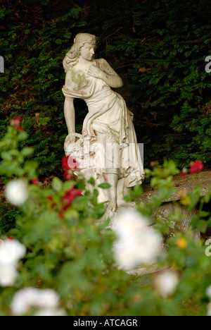 ein Neo klassische griechische römische Gartenstatue inmitten von weißen und roten Rosen in einem gepflegten Herrenhaus Garten Stockfoto