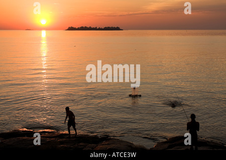 Zwei junge Männer am Ufer des Río De La Plata in Coloñia del Sacramento Uruguay Silhouette von der untergehenden Sonne Stockfoto