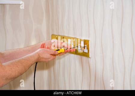 Person mit Schraubendreher Steckdose Abdeckung von Wand entfernen Stockfoto