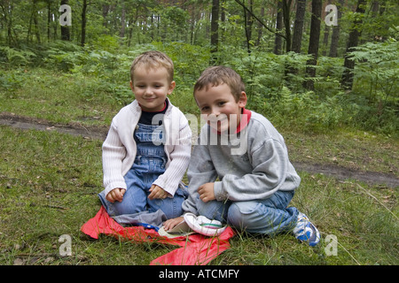 Zwei jungen sitzen auf Wiese, spielen im Wald Stockfoto